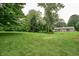 Lush backyard featuring mature trees and a well-maintained lawn with the house in the distance at 1000 Janet Dr, Greenwood, IN 46142