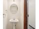 Half bath showcases a pedestal sink, oval mirror, and a door to another room at 1012 S Montgomery Rd, Greenwood, IN 46143
