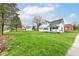View of the home with a large grassy yard, mature trees, and a detached garage at 121 Illinois St, Shirley, IN 47384