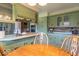 View of kitchen with stainless steel appliances, green cabinets, and a wooden dining room table at 12166 N Bray Rd, Mooresville, IN 46158