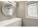 Bright bathroom with a large round mirror, modern vanity, and a window offering natural light at 123 W 81St St, Indianapolis, IN 46260