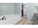 Bathroom featuring a tub, grey cabinets, wood floors, and a view of the closet at 12753 Bristow Ln, Fishers, IN 46037