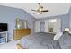 Bedroom with a ceiling fan, blue walls, dresser, bed and a view of the bathroom through an open door at 12753 Bristow Ln, Fishers, IN 46037