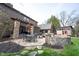 Spacious backyard featuring a stone patio with dining table, fire pit, built-in seating, and well-manicured lawn at 13599 Brentwood Ln, Carmel, IN 46033