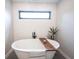 Elegant soaking tub with a wooden tray, modern faucet, and accent wall at 13599 Brentwood Ln, Carmel, IN 46033