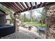 Covered patio with stone columns, pergola, outdoor seating, and a view of the landscaped backyard with fire pit at 13599 Brentwood Ln, Carmel, IN 46033