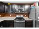 Close-up showcasing the stainless steel oven, microwave, granite countertops, and dark wood cabinets at 13820 N Cardonia Dr, Camby, IN 46113
