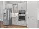 Kitchen featuring stainless steel refrigerator, built-in double ovens, and white cabinetry at 16422 Brigham Ln, Westfield, IN 46074