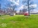 Sprawling backyard featuring a large green lawn, storage sheds, and mature trees, perfect for outdoor activities at 1734 Bittersweet Dr, Anderson, IN 46011