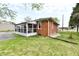 Rear exterior view of the home showing the sunroom and brick facade with ample backyard lawn at 1934 N Arlington Ave, Indianapolis, IN 46218