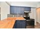 Updated kitchen features blue cabinets, butcher block counters, stainless steel appliances, and mosaic tile backsplash at 1934 N Arlington Ave, Indianapolis, IN 46218