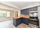 Modern kitchen featuring blue cabinets, wood countertops, stainless steel appliances, and a bright, window-filled breakfast nook at 1934 N Arlington Ave, Indianapolis, IN 46218