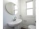 Clean, well-lit powder room with a pedestal sink, round mirror, and modern fixtures at 2226 N Capitol Ave, Indianapolis, IN 46208