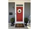 A welcoming red front door with a white wreath and potted plants, set against gray siding with a stylish doormat at 2419 N Park Ave, Indianapolis, IN 46205