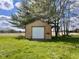 A shed with brown wooden exterior and a white garage door is surrounded by lush green grass and trees at 2715 S 300 E, Anderson, IN 46017