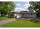 View of the home's back exterior and detached garage with a spacious driveway and grassy area at 3140 Bonham Dr, Indianapolis, IN 46222