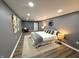 A bedroom with wood flooring, gray walls, decorative pillows, and a view of a sitting area with chair at 3233 N Tacoma Ave, Indianapolis, IN 46218