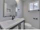 Bathroom featuring white cabinets and toilet, dark fixtures, and a rounded mirror above the sink at 451 N Gray St, Indianapolis, IN 46201