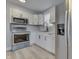Updated kitchen with stainless steel appliances, white cabinets, gray walls, and wood-look floors at 451 N Gray St, Indianapolis, IN 46201