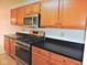 A kitchen features wood cabinets, black countertops, and stainless-steel appliances at 4959 Clarkson Dr, Indianapolis, IN 46254