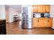 Open-concept kitchen with stainless steel refrigerator, wood cabinets, and view of the entryway beyond at 504 W Dwain, Shelbyville, IN 46176