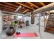 Unfinished basement with exposed beams, storage shelves, exercise equipment, and adjacent laundry area at 5277 Kingsley Dr, Indianapolis, IN 46220