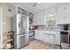 Well-lit kitchen with white cabinets, stainless steel appliances, a mosaic backsplash, and stylish tiled floors at 5277 Kingsley Dr, Indianapolis, IN 46220