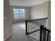 Carpeted landing with black railing, leading to the upper level, with a bright window at 5692 Coulter Way, Greenwood, IN 46143