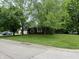A well-manicured lawn enhances this home's curb appeal, complemented by mature trees providing shade at 605 Queenswood Dr, Indianapolis, IN 46217
