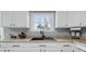 A well-lit kitchen with stainless steel sink and fixtures, complemented by white cabinetry and countertops at 6303 Bertha St, Indianapolis, IN 46241