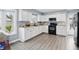 Bright kitchen with stainless steel appliances, white cabinets, and gray flooring at 6303 Bertha St, Indianapolis, IN 46241