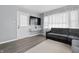 Cozy living room featuring gray walls, wood floors, and a comfortable gray sectional sofa by a large window at 6303 Bertha St, Indianapolis, IN 46241