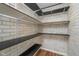 A walk-in pantry with white brick walls, black shelves, and wood flooring for organized storage at 7115 N Lyndhurst Xing, McCordsville, IN 46055