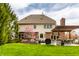 Home's back exterior features a covered patio, outdoor seating, lush greenery, and blossoming tree at 7326 Elm Ridge Dr, Indianapolis, IN 46236