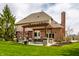 Home's back exterior features a covered patio, outdoor seating, and lush green yard at 7326 Elm Ridge Dr, Indianapolis, IN 46236