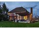 Home's back exterior features a covered patio, outdoor seating, and lush green yard at twilight at 7326 Elm Ridge Dr, Indianapolis, IN 46236