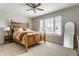 Bright bedroom features a wooden bed frame, ceiling fan, and window providing ample natural light at 7326 Elm Ridge Dr, Indianapolis, IN 46236