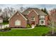 Charming brick home with a red front door, lush green lawn, and beautifully landscaped front yard at 7326 Elm Ridge Dr, Indianapolis, IN 46236