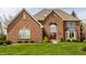 Stunning brick home featuring a red front door, well-manicured lawn, and mature landscaping at 7326 Elm Ridge Dr, Indianapolis, IN 46236