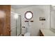 Compact bathroom with a glass-enclosed shower, toilet, and a classic octagonal window for natural light at 803 S School St, Brownsburg, IN 46112