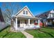 Charming two-story home featuring a gabled roof, inviting front porch and well-manicured lawn under a clear blue sky at 106 N Linwood Ave, Indianapolis, IN 46201