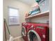 Laundry room with a red washer and dryer, storage shelves, and a window at 106 N Linwood Ave, Indianapolis, IN 46201