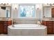 Luxurious bathroom featuring a soaking tub with decorative window and dual vanities at 13225 Gatman Ct, Carmel, IN 46032