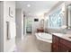 Large bathroom featuring a soaking tub, dual vanities, and a decorative glass window at 13225 Gatman Ct, Carmel, IN 46032