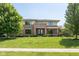 Two story brick home with a large front lawn, manicured shrubs and mature trees creating a welcoming and picturesque setting at 13225 Gatman Ct, Carmel, IN 46032