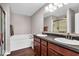 Bright bathroom featuring a soaking tub, double vanity with dark cabinets and granite countertop at 159 Longleaf Ln, Greenfield, IN 46140