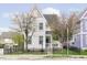 Charming two-story home with a black metal fence and mature trees in full bloom at 2263 N Delaware St, Indianapolis, IN 46205