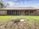 Rear view of a brick home showcasing a screened-in porch, covered patio, and a spacious backyard at 2810 Winterway Dr, Shelbyville, IN 46176