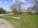 Well-maintained brick ranch home with a three-car garage, beautiful lawn, and mature trees on a sunny day at 2810 Winterway Dr, Shelbyville, IN 46176