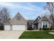Charming brick home featuring a two-car garage, manicured lawn, and classic architectural details under a beautiful sky at 2890 Trillium Way, Columbus, IN 47201